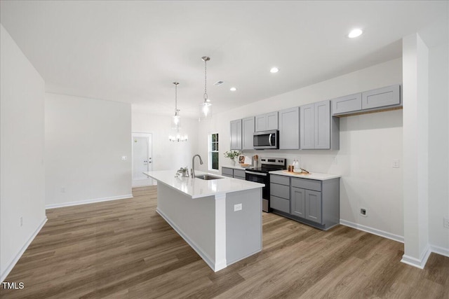 kitchen featuring appliances with stainless steel finishes, sink, a kitchen island with sink, and gray cabinetry