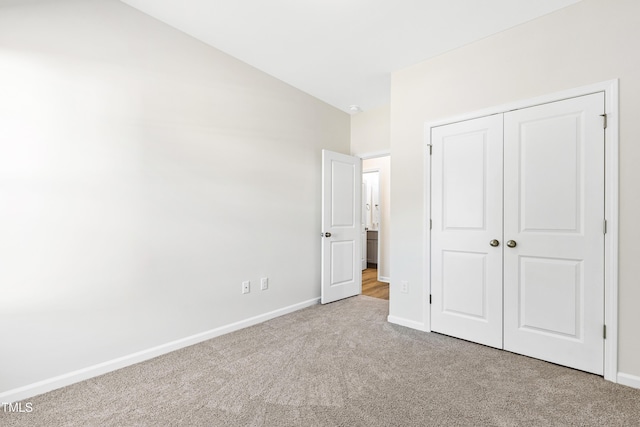 unfurnished bedroom featuring light carpet and a closet