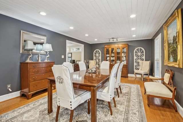 dining room featuring ornamental molding, a healthy amount of sunlight, wood ceiling, and light hardwood / wood-style flooring