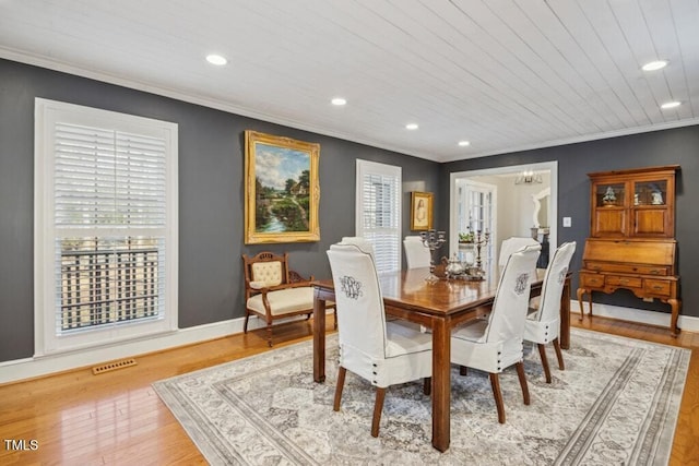 dining space with light hardwood / wood-style flooring, a wealth of natural light, ornamental molding, and an inviting chandelier