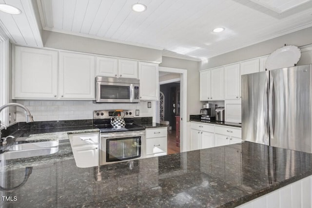 kitchen with appliances with stainless steel finishes, white cabinetry, sink, dark stone countertops, and ornamental molding