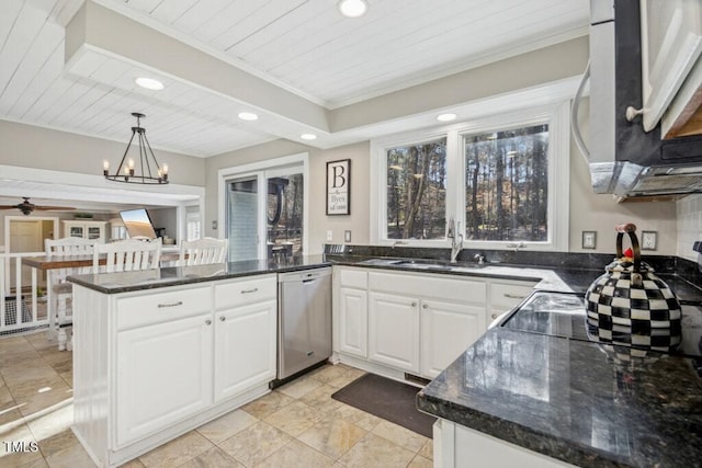 kitchen featuring pendant lighting, stainless steel appliances, kitchen peninsula, white cabinets, and dark stone counters