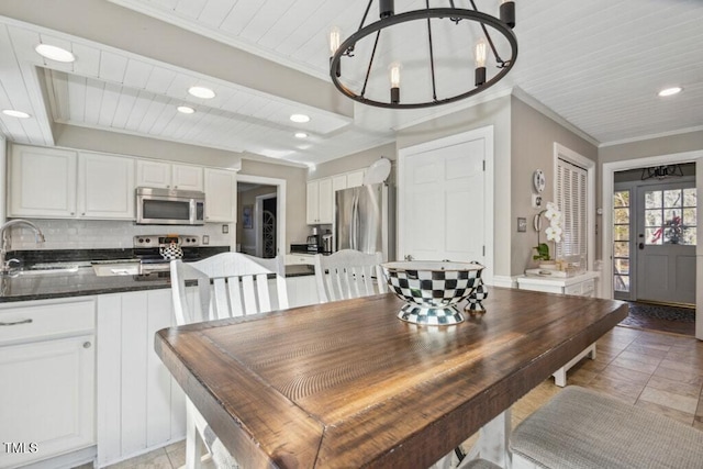 dining room with ornamental molding, sink, and a chandelier