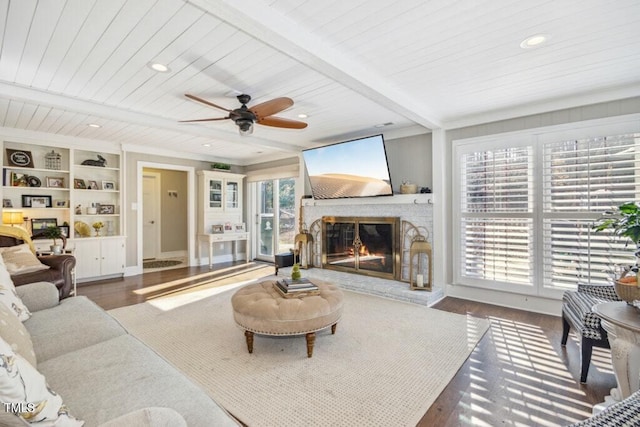 living room featuring beamed ceiling, dark hardwood / wood-style flooring, wood ceiling, a brick fireplace, and built in shelves