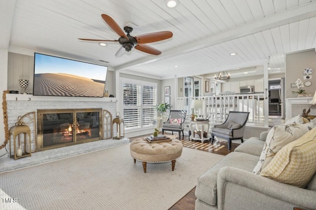 living room featuring hardwood / wood-style floors, ceiling fan with notable chandelier, and beam ceiling