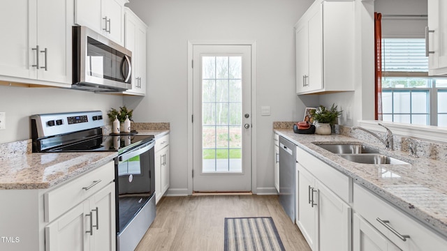 kitchen featuring white cabinetry, light hardwood / wood-style floors, stainless steel appliances, light stone counters, and sink