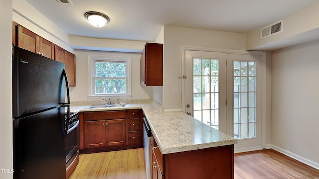 kitchen with sink, kitchen peninsula, stainless steel appliances, and light wood-type flooring