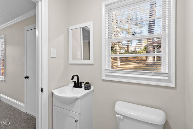 bathroom featuring a wealth of natural light, toilet, vanity, and crown molding