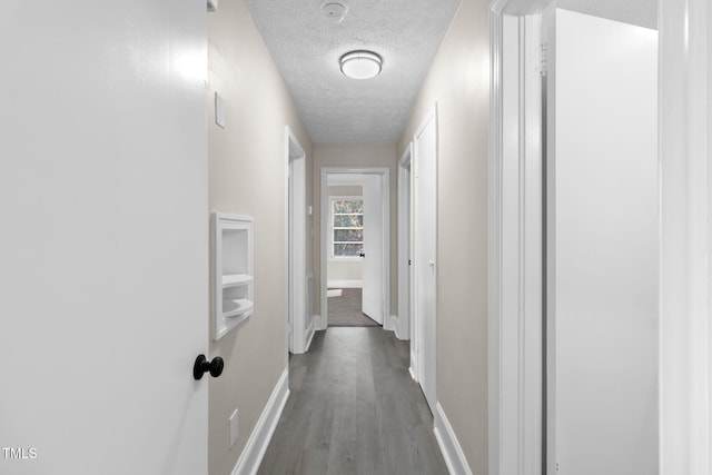 hallway with light wood-type flooring and a textured ceiling