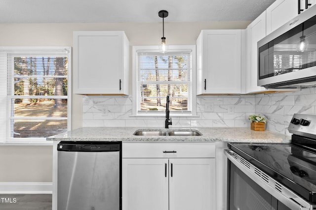 kitchen with sink, light stone counters, stainless steel appliances, and white cabinetry