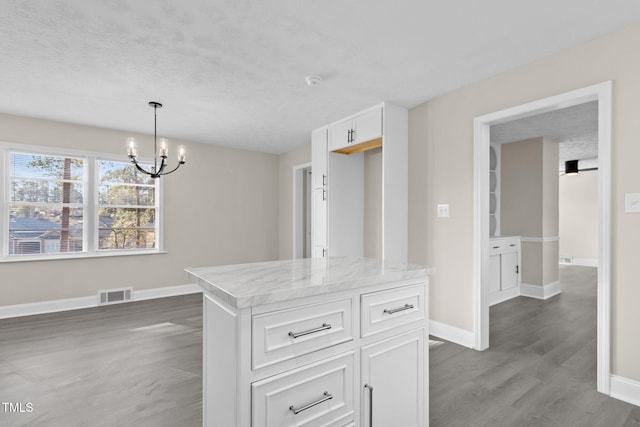 kitchen with decorative light fixtures, an inviting chandelier, light stone countertops, white cabinets, and dark hardwood / wood-style flooring