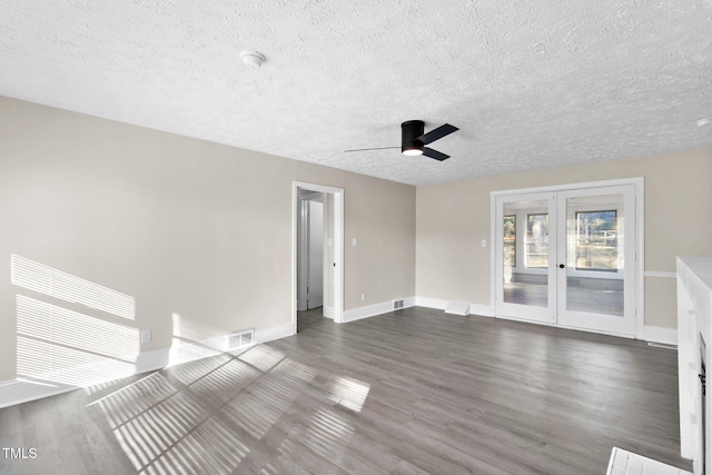 empty room with ceiling fan, a textured ceiling, dark hardwood / wood-style flooring, and french doors