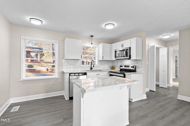 kitchen featuring stainless steel appliances, a center island, decorative light fixtures, white cabinets, and sink