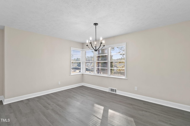 unfurnished dining area with a textured ceiling, dark hardwood / wood-style flooring, and a notable chandelier