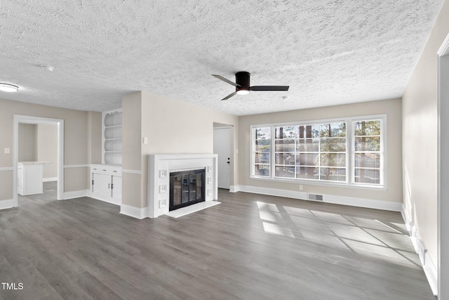 unfurnished living room with ceiling fan, hardwood / wood-style floors, built in features, and a textured ceiling