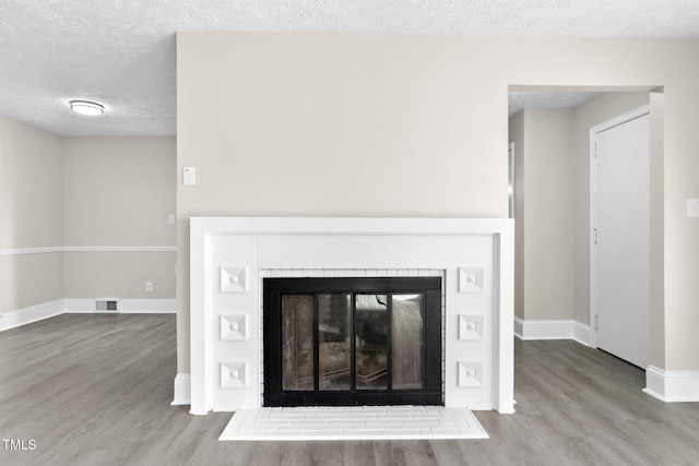 details with a textured ceiling, a fireplace, and wood-type flooring