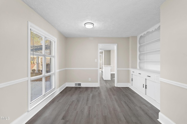 unfurnished dining area featuring dark wood-type flooring and a textured ceiling