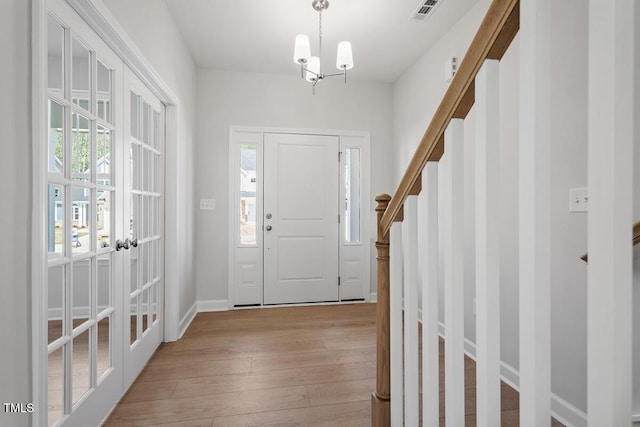 foyer entrance with light wood-type flooring, visible vents, stairway, and a healthy amount of sunlight