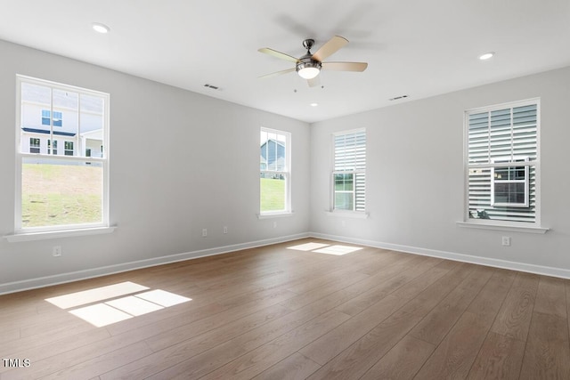 unfurnished room featuring wood finished floors, a ceiling fan, baseboards, and plenty of natural light