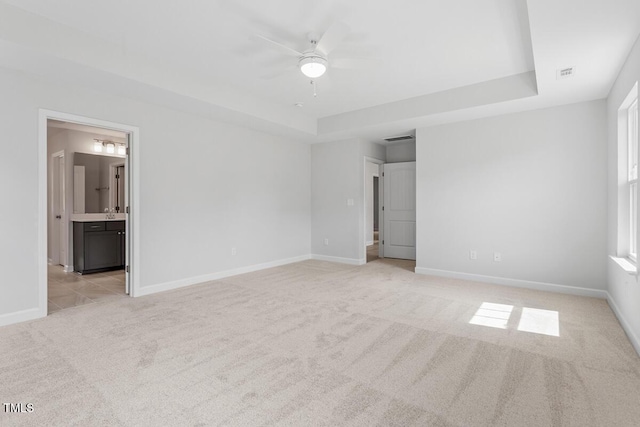 unfurnished bedroom featuring visible vents, light carpet, and a tray ceiling