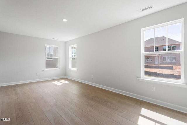 spare room with baseboards, wood finished floors, visible vents, and recessed lighting