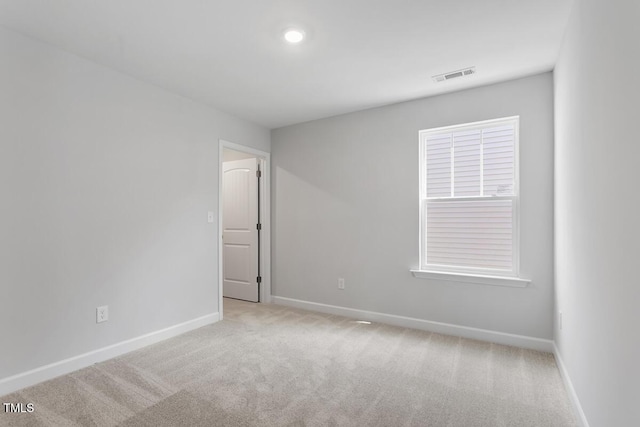 empty room with visible vents, baseboards, and light colored carpet