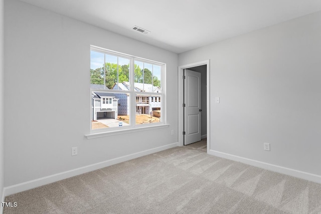 spare room featuring carpet floors, visible vents, and baseboards