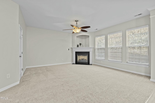 unfurnished living room with light carpet, a multi sided fireplace, and ceiling fan