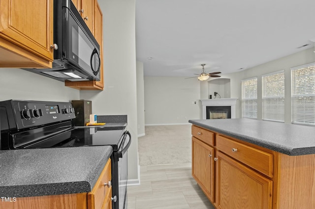 kitchen featuring black appliances, a kitchen island, ceiling fan, and light carpet