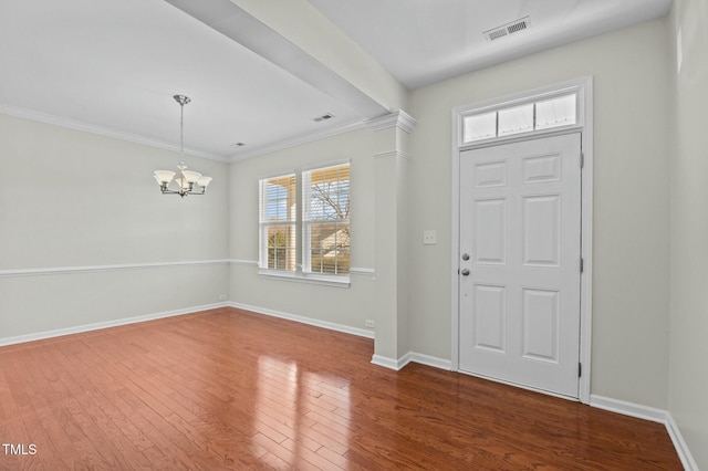 entryway with crown molding, a notable chandelier, and dark hardwood / wood-style flooring