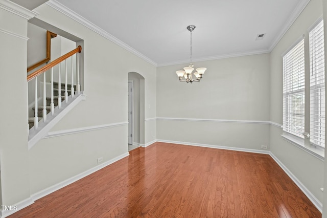 unfurnished room featuring hardwood / wood-style flooring, crown molding, and an inviting chandelier