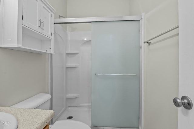 bathroom with toilet, a shower with door, and vanity