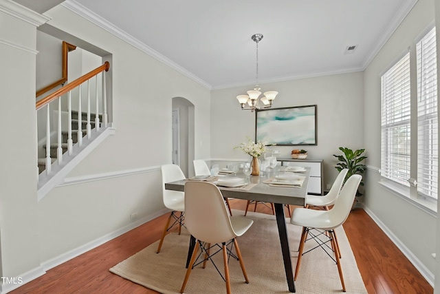 dining area with hardwood / wood-style flooring, a chandelier, and ornamental molding