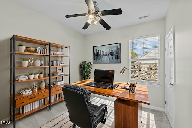 carpeted home office featuring ceiling fan