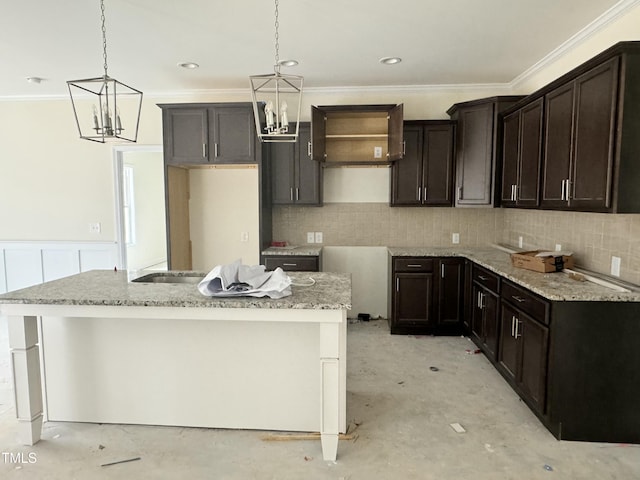 kitchen with dark brown cabinetry, hanging light fixtures, and a center island with sink