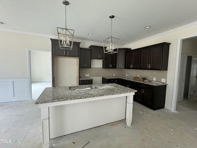 kitchen featuring crown molding, a center island, light stone counters, and decorative light fixtures