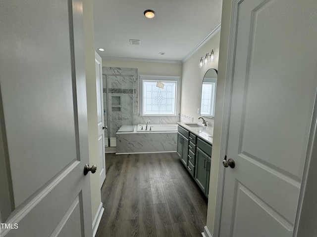 full bath with visible vents, wood finished floors, a garden tub, crown molding, and vanity