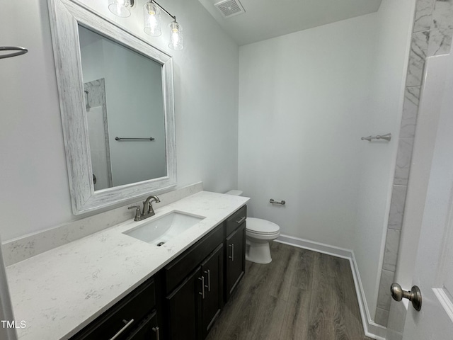 bathroom featuring toilet, wood finished floors, vanity, visible vents, and baseboards