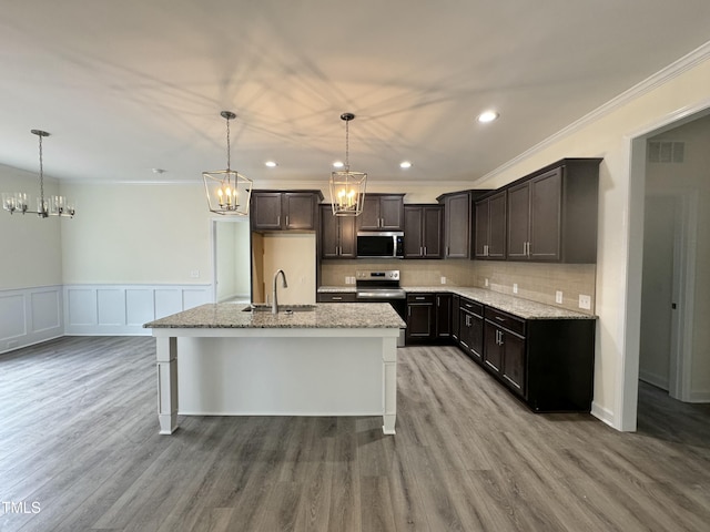 kitchen featuring stainless steel appliances, a sink, light stone counters, and tasteful backsplash