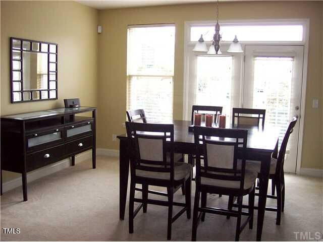 dining space with light carpet and a notable chandelier