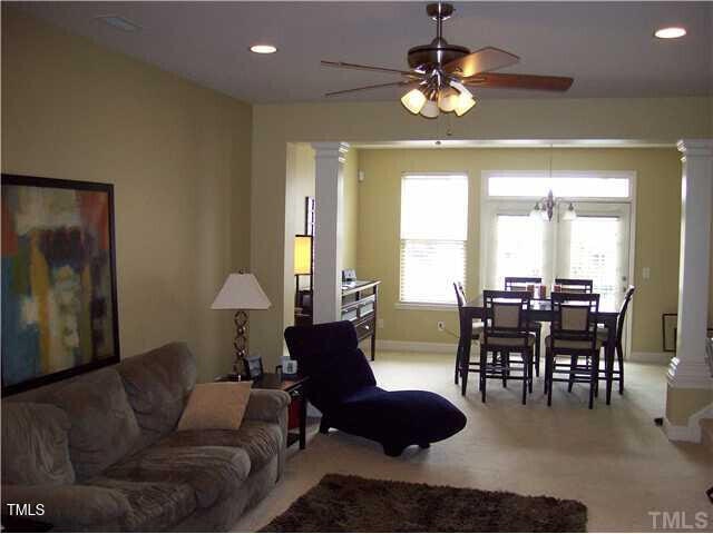 living room featuring ceiling fan, light colored carpet, and ornate columns