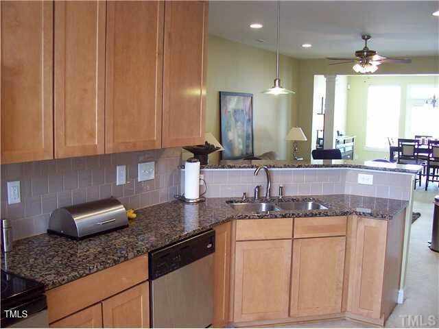 kitchen featuring ceiling fan, dark stone countertops, stainless steel dishwasher, decorative backsplash, and sink