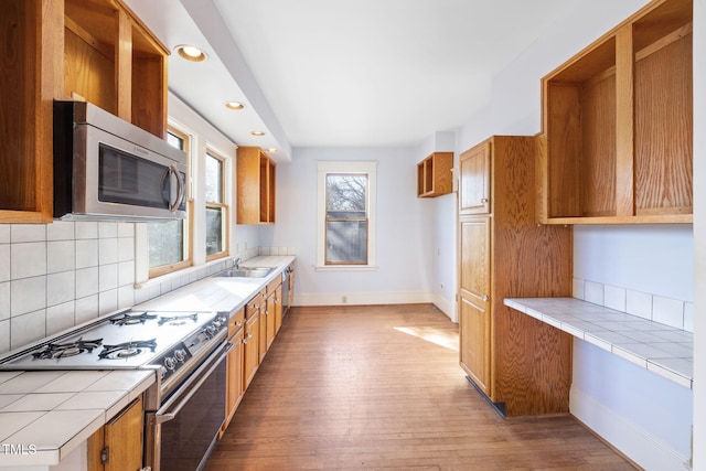 kitchen with stainless steel appliances, tile counters, dark hardwood / wood-style flooring, and decorative backsplash