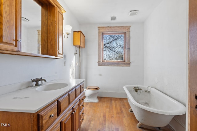 bathroom featuring vanity, a bath, wood-type flooring, and toilet