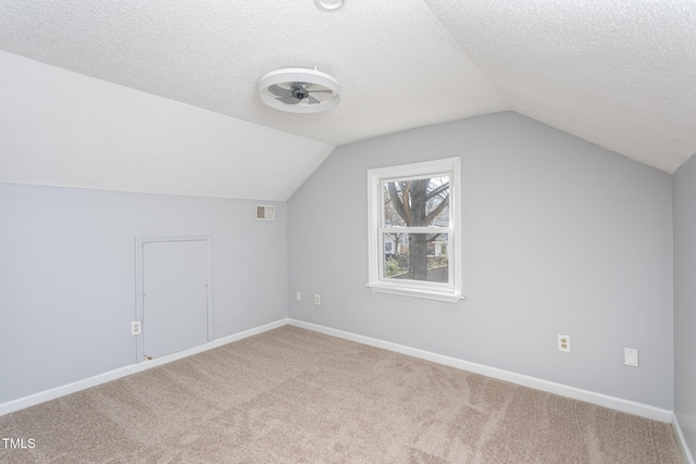 additional living space featuring a textured ceiling, carpet floors, visible vents, and baseboards