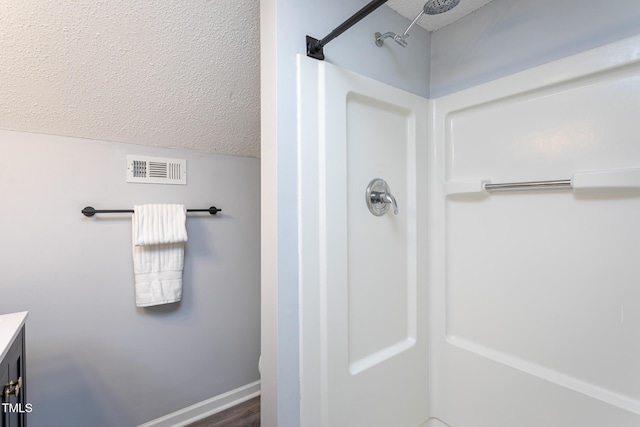 full bath featuring visible vents, walk in shower, a textured ceiling, and vanity