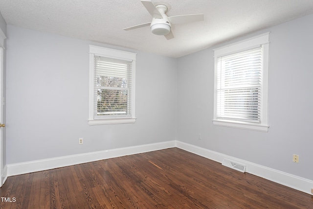 spare room with dark wood finished floors, visible vents, plenty of natural light, and baseboards