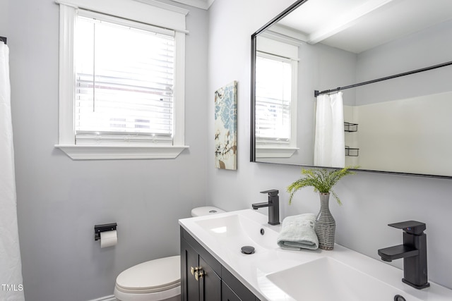 bathroom with toilet, curtained shower, double vanity, and a sink