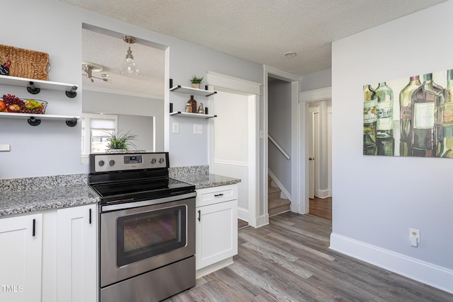 kitchen with electric range, light stone counters, a textured ceiling, white cabinetry, and open shelves