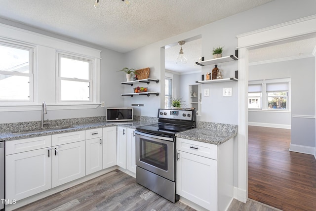 kitchen featuring appliances with stainless steel finishes, wood finished floors, white cabinetry, open shelves, and a sink